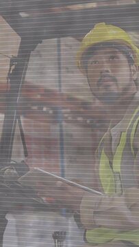 Vertical video: Depot man after log check looking up checking forklift wheel via mesh for safety