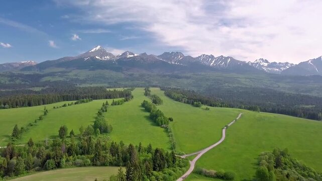 Panoramic view of a lush green valley landscape with high mountain ranges in the distant background