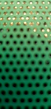 Green perforated metal texture with circular holes, industrial grid pattern, abstract background ideal for technology, construction, and modern design