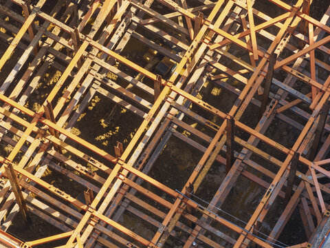 Aerial view of building foundation engineering with a complex grid of orange steel shoring beams over an excavation site in Taiwan.