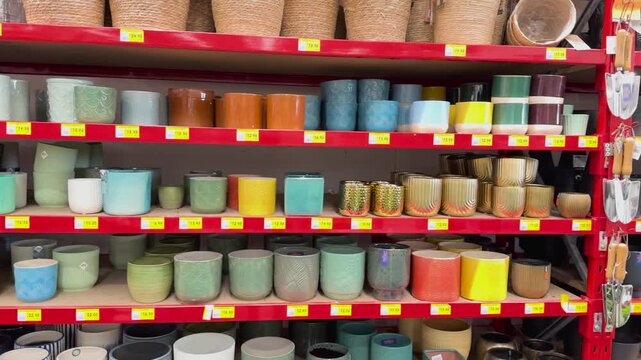 A dynamic footage of shelves filled with colorful and patterned ceramic plant pots and gardening tools in a vibrant home goods store.