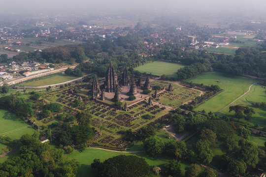 Aerial view of the ancient Prambanan Temple complex with its towering stone spires surrounded by lush green lawns and trees in Kecamatan Prambanan, Daerah Istimewa Yogya, Indonesia.