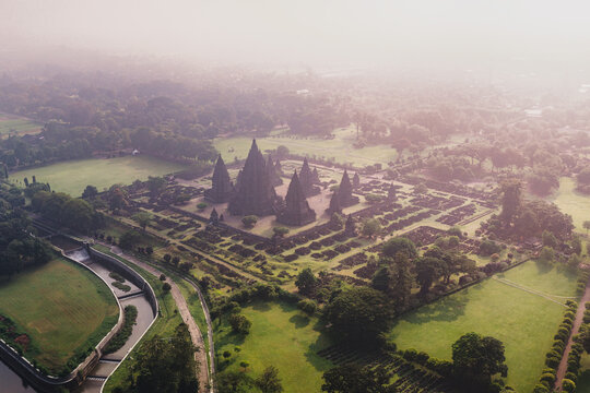 Aerial view of the Prambanan Temple complex with its iconic stone spires surrounded by lush green parks and morning mist Kecamatan Prambanan, Daerah Istimewa Yogya, Indonesia.