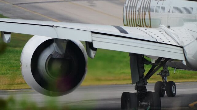 LISBON, PORTUGAL - FEBRUARY 8, 2026: Emirates Boeing taxiing on runway, close-up of turbofan engine and wing underside with main landing gear extended. Emirates is a major international airline based