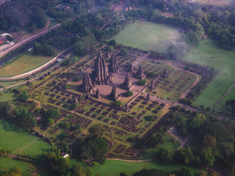 Aerial view of Prambanan Temple complex with its towering stone structures surrounded by lush green gardens and morning mist Kecamatan Prambanan, Daerah Istimewa Yogya, Indonesia.