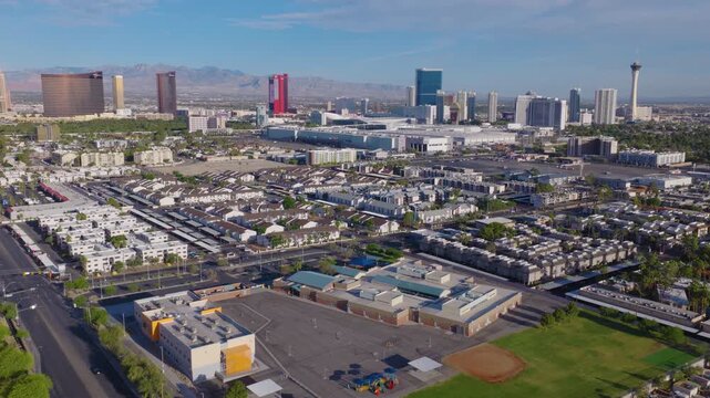 Aerial moving shot of Las Vegas suburbs and Strip skyline and mountains 