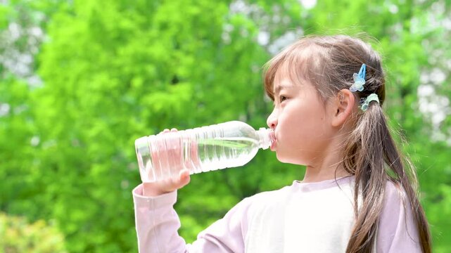 新緑の中熱中症予防など、小学生の子どもの水を飲む水分補給のイメージの横顔動画クローズアップ