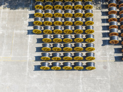 Aerial view of rows of large black cable reels with yellow rims neatly organized on a concrete industrial yard in Taiwan.
