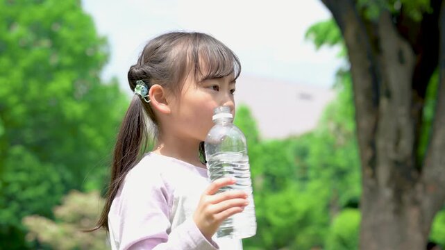新緑の中熱中症予防など、小学生の子どもの水を飲む水分補給のイメージの動画クローズアップ