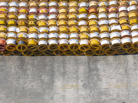 Aerial view of many yellow and white industrial cable reels stacked in rows on a concrete surface in Taiwan.