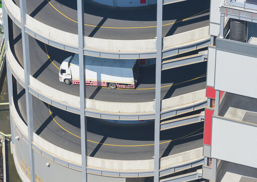 Aerial view of a white truck driving on a spiral ramp of a logistics warehouse with industrial architecture in Taiwan.