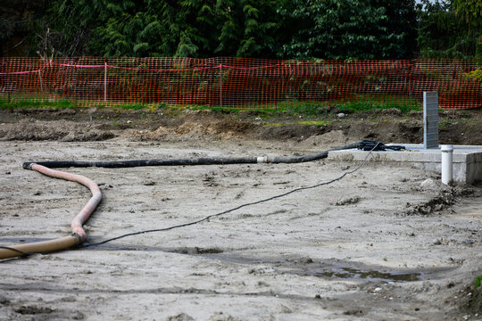 Temporary industrial hose, running across construction site, removing excess water from storm water vault access point
