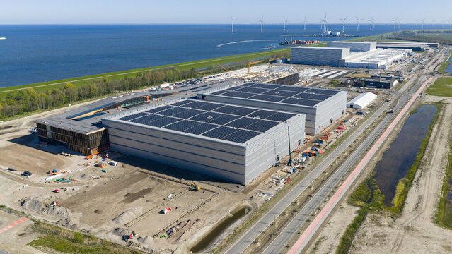 Aerial view of the JYSK DCL construction site featuring large warehouses with solar panels near the coast and wind turbines Lelystad, Flevoland, Netherlands.