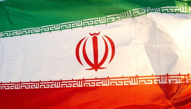 The Iranian flag waves with green, white, and red stripes, central emblem, and Kufic script borders, symbolizing national identity, Islamic heritage, and cultural pride.