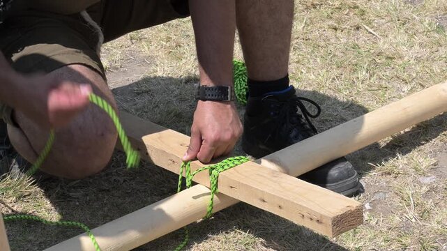 man making lashings to join two pieces of wood