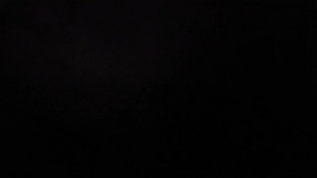Dramatic lightning storm at night, powerful electrical flashes illuminating dark purple clouds, extreme weather over silhouetted trees