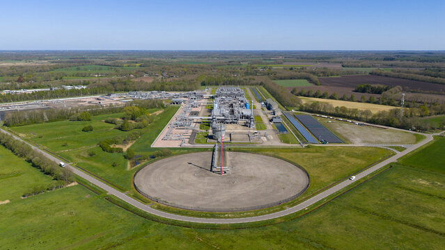 Aerial view of the UGS Norg gas storage facility featuring industrial infrastructure and a circular structure surrounded by green fields and forests in Langelo, Drenthe, Netherlands.