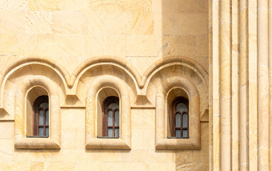 Naklejka premium Architectural Elegance: A close-up view showcasing the intricate facade of a classical building with an arrangement of arched windows, paired with a stately column.