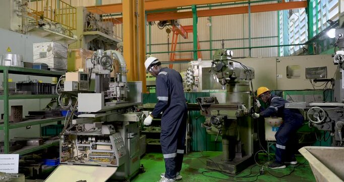two african adult male workers operate separate machines across workshop, coordinate production tasks, safety PPE workflow and equipment monitoring support industrial teamwork daily