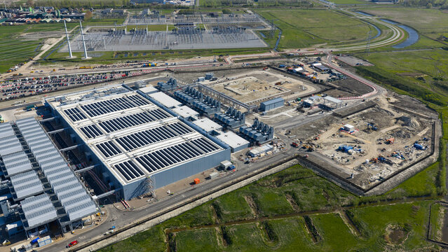 Aerial view of Datacenter Westpoort featuring solar panels on the roof and an adjacent construction site near a power substation Groningen, Groningen, Netherlands.