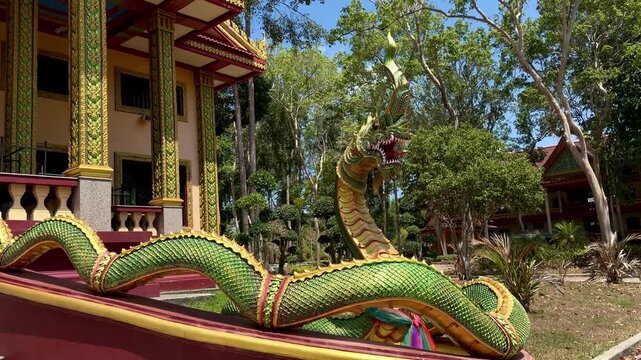 Long green Naga sculpture at Wat Bang Thong temple in Krabi, Thailand. Traditional Thai Buddhist art and architecture. Majestic serpent statue guarding the sacred landmark.