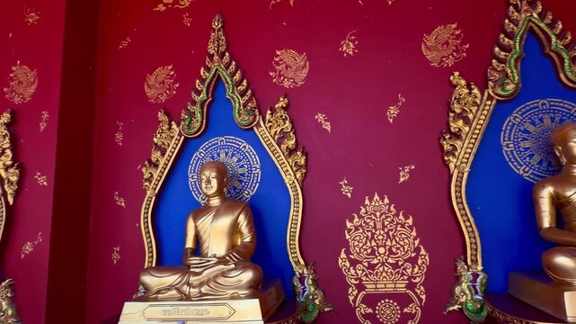 Row of golden Buddha statues against red walls in Wat Bang Thong temple, Krabi, Thailand. Ornate Thai architecture and spiritual atmosphere in a famous Buddhist landmark.