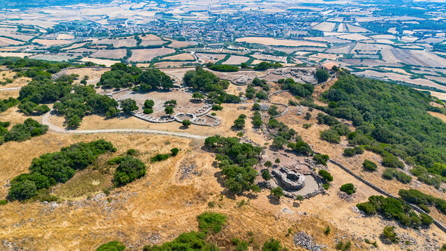 Aerial view of the Nuragic Sanctuary of Santa Vittoria, an ancient archaeological complex with stone ruins on the basaltic plateau of Serri, Sardinia, Italy