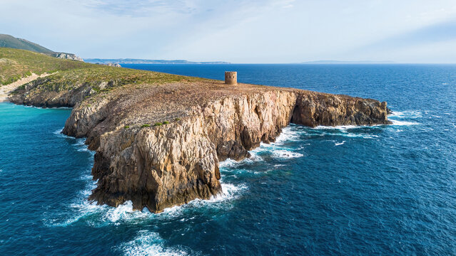 Aerial view of the rugged limestone cliffs and the historic Spanish watchtower at Cala Domestica, Buggerru, Sardinia, Italy