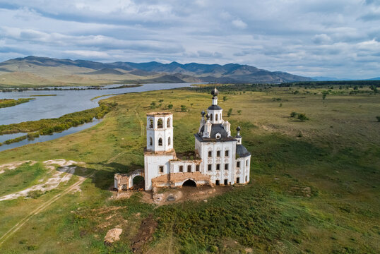 Holy Trinity Church a historic baroque structure overlooks Selenga River near mountains on a cloudy day