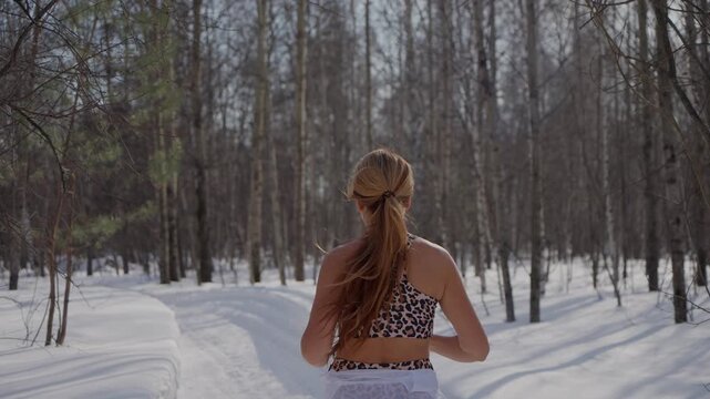 Fitness Woman running winter at forest nature. Fit sportswoman jogging on path in park on snowy winter day. Recreation, snowy weather, winter day.