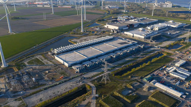 Aerial view of the Google Data Center complex surrounded by wind turbines and green fields in Eemshaven, Groningen, Netherlands.