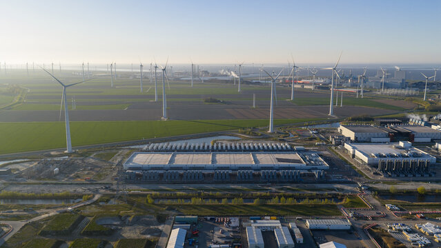 Aerial view of the Google Data Center surrounded by wind turbines and green fields under a clear sky in Eemshaven, Groningen, Netherlands.
