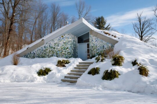 Earth-sheltered house with a mosaic recycled glass wall in winter