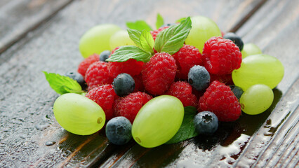 closeup shot of berry mix containing raspberry blueberry and grapes on wet dark desk © Yasin_Alam