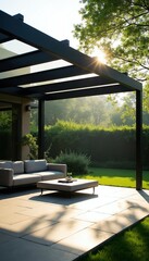 Naklejka premium Modern patio with sofa and table under pergola. Outdoor furniture set on stone tiles near green lawn and garden hedge. Bright sun shines through tree leaves.