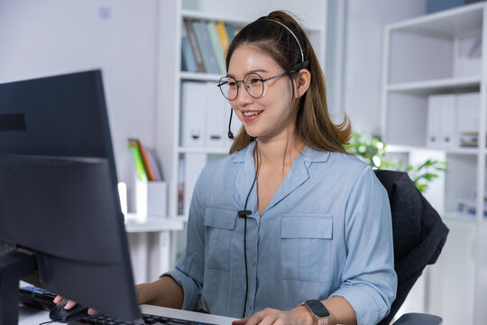 Customer service headset computer office woman smiling Customer service agent wearing headset computer desk modern office, smiling during online support call, remote work concept with professional