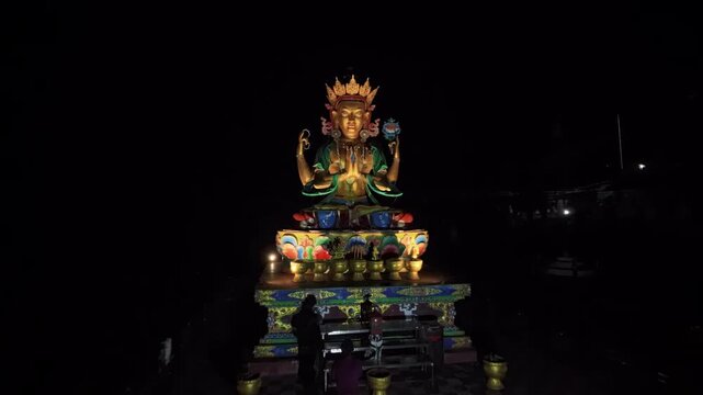 Drone aerial night footage of illuminated Chenrezig Avalokiteśvara statue in Chitrey Nepal, glowing Himalayan Buddhist landmark, spiritual tourism, cinematic shrine view