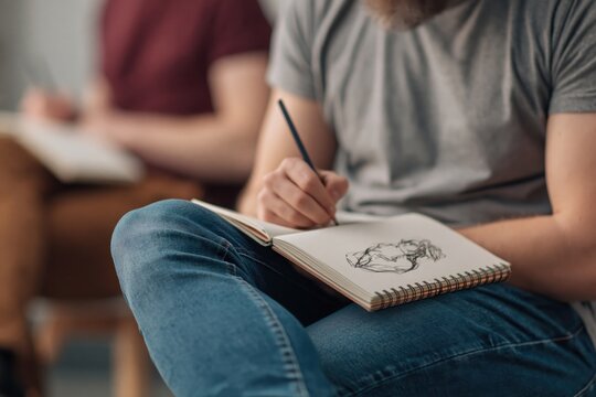 Creative expression and artistic pursuits Man sketching in a notebook with a pencil during art class exploring drawing techniques and developing creative skills. High quality photo