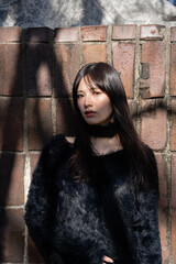 Fototapeta premium 木漏れ日が顔に差す, 冬の装いの女性。屋外でのファッションポートレート
