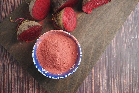 Beetroot powder and fresh beets on wooden surface