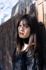 Fototapeta premium 木漏れ日が顔に差す、冬の装いの女性。屋外でのファッションポートレート