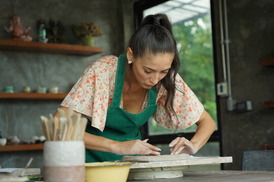 A young woman makes a ceramic plate in a workshop