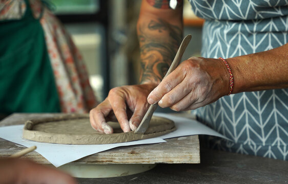 An adult man makes a ceramic plate in a workshop