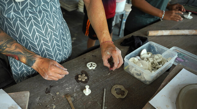 An adult man makes a ceramic plate in a workshop