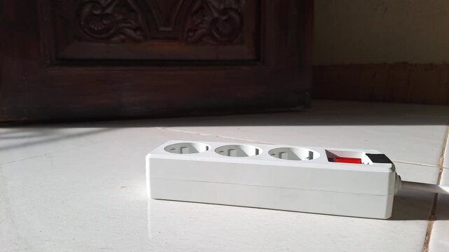 Close-up of an Asian man's hand plugging in and unplugging an extension cord into a power strip. The footage shows switching the power button on and off, connecting an electric cable for charging.