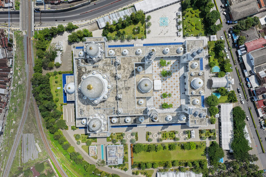 Aerial view of Sheikh Zayed Grand Mosque Solo Surakarta featuring white domes, minarets, and a courtyard surrounded by green gardens in Kecamatan Banjarsari, Jawa Tengah, Indonesia.