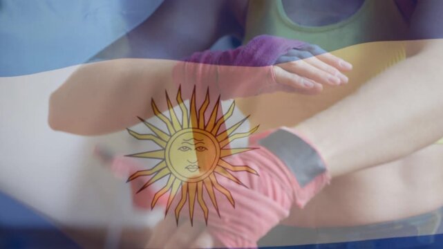 Woman grabbing pink wrap and winding wrist for boxing, flag overlay centering sun emblem