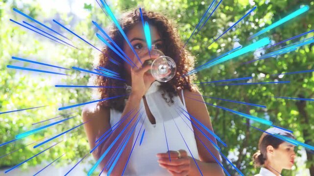 Woman raising stemmed glass and sipping at marketing event, radial streaks radiating around her