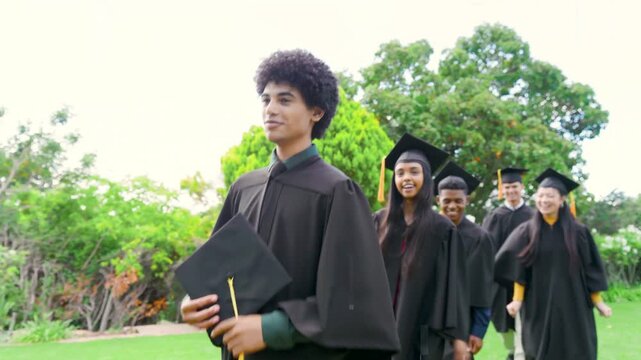 Lead male graduate holding cap leading graduation march, camera pulling back, pixelation masking