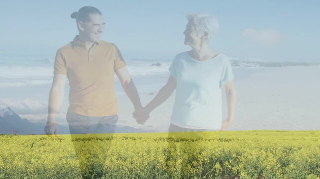 Pair facing, stepping walking hand-in-hand on beach with lower yellow flower overlay for wellness